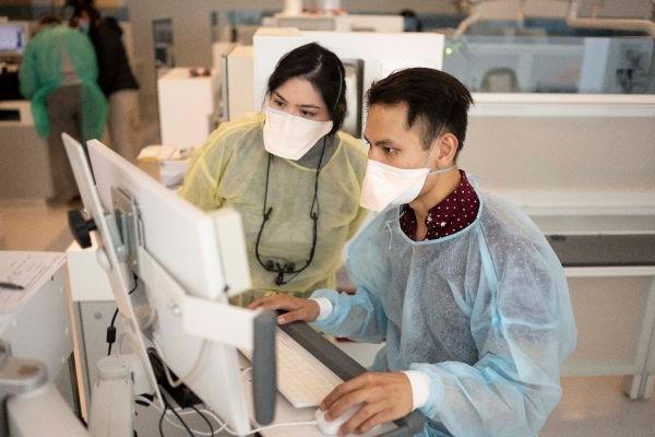 two gowned people at a computer 在诊所/lab